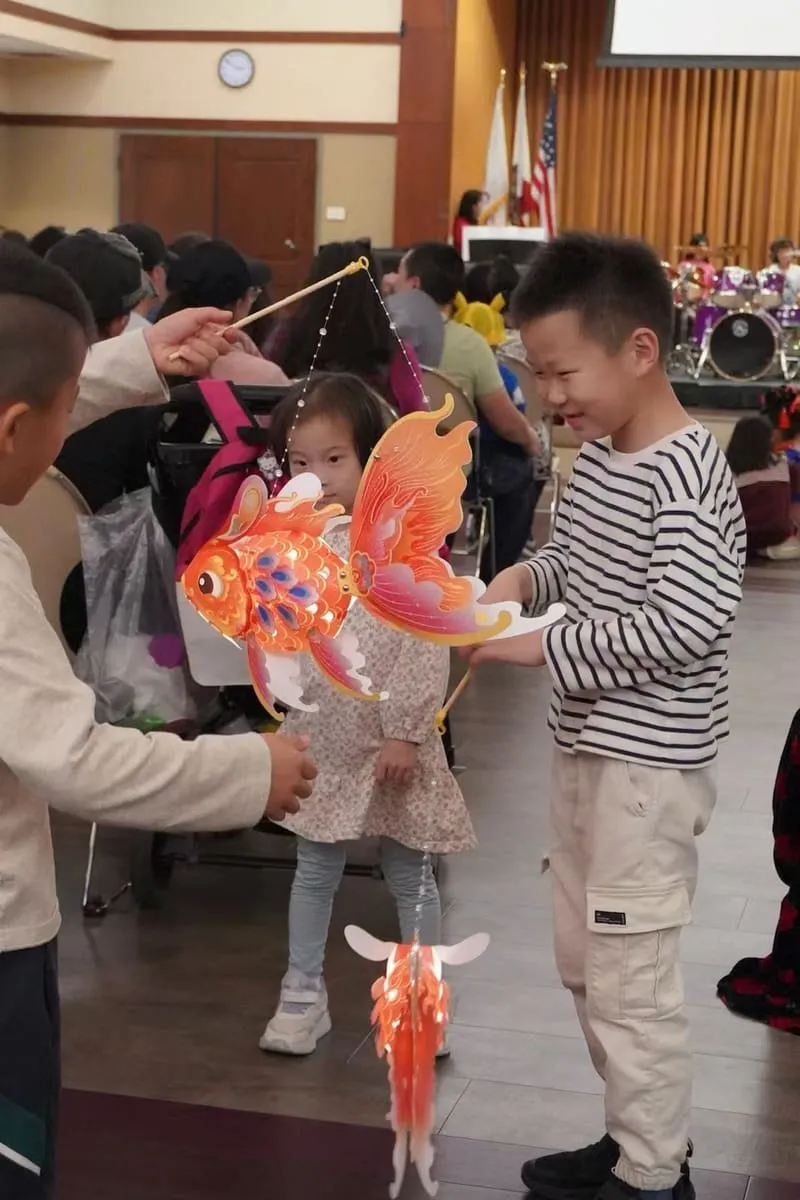 Children carry a paper goldfish lantern.