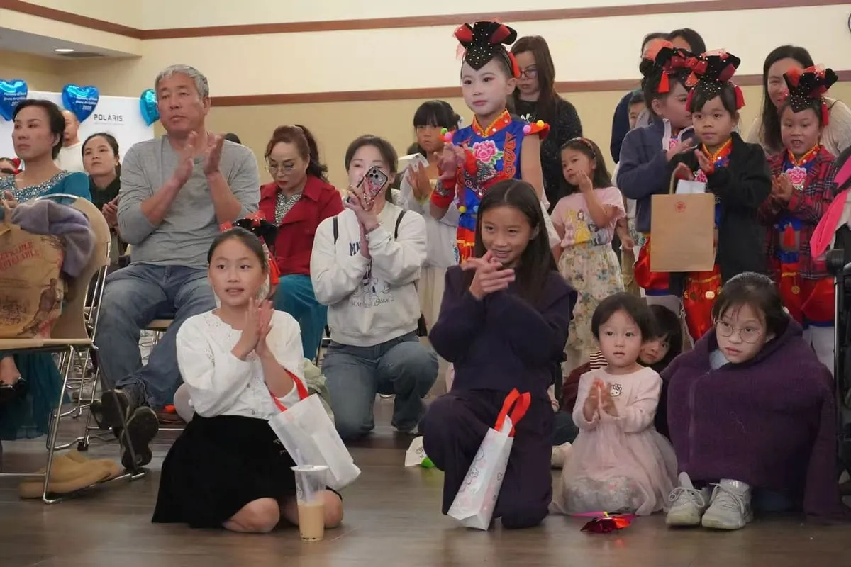 Families and young performers in costume watch the show from the floor.