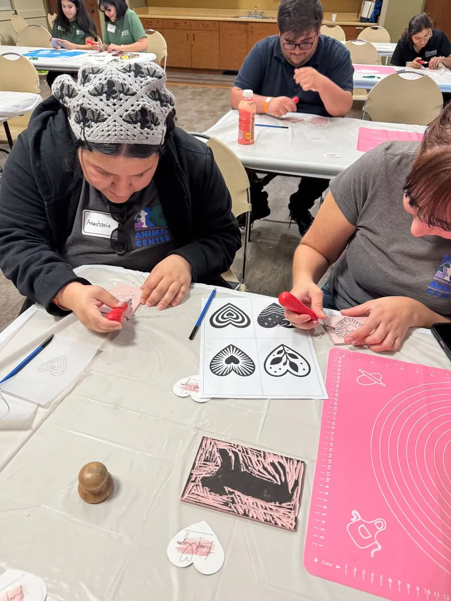 Participants press clay into heart molds at a craft table.
