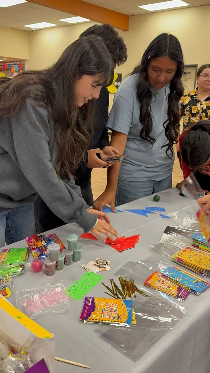 Teenagers sort beads and craft supplies at a workshop table.