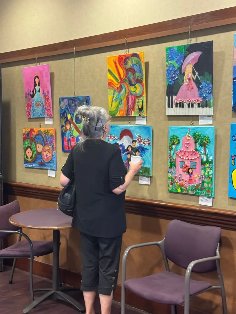 A visitor studies a wall of colorful paintings.