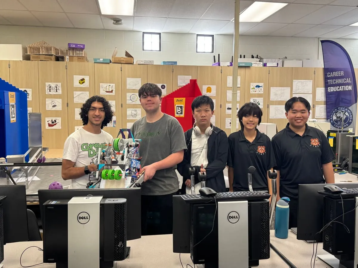 A robotics team stands with its robot in a computer lab.