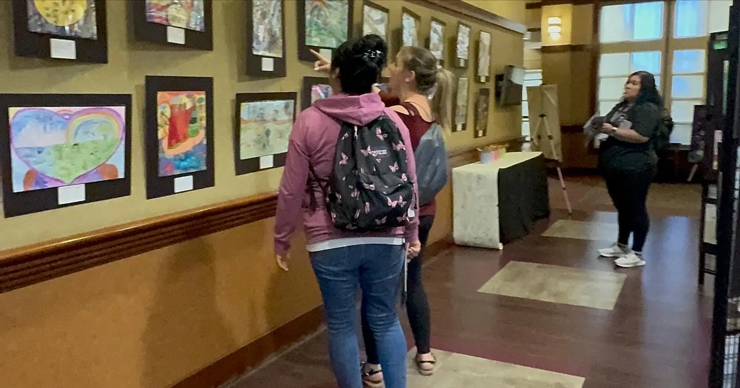 Visitors look at framed artwork along the community center corridor.